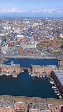 4K aerial vertical video of Liverpool Royal Albert Dock and Metropolitan Cathedral. Cinematic drone footage of historic waterfront and city skyline. Iconic UK travel view for mobile reels.