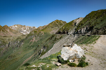 Scenic Alpine Mountain Road Traversing Green Valleys Under a Clear Blue Sky