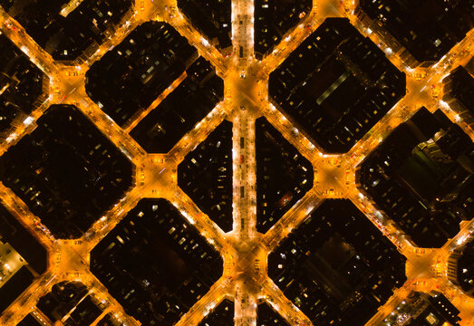 Aerial view of a grid-patterned cityscape ablaze with warm light, revealing the unique urban layout of Barcelona, Catalonia, Spain.