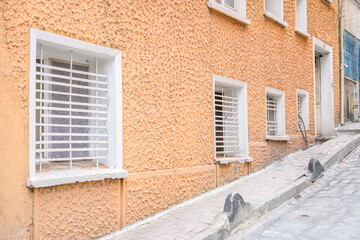 A building with a white trim and orange paint. The windows are white and the building is on a hill.