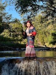 Modern ethnic fashion: Young woman showcasing fusion Hmong style in a natural setting.