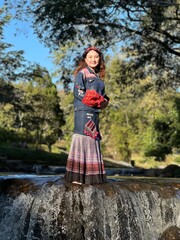 Modern ethnic fashion: Young woman showcasing fusion Hmong style in a natural setting.