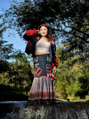 Portrait of a young traveler wearing ethnic hill tribe clothing by a river in Northern Thailand.
