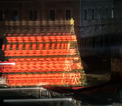 Abstract long exposure motion blur of illuminated Christmas tree and building lights in Jerusalem.