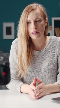 A woman shares advice on vlogging while recording in her studio.