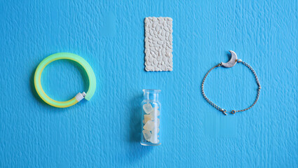 Artistic Still Life Composition Featuring a Neon Bracelet, Textured Tile, Small Bottle with Stones, and Crescent Bracelet on a Vibrant Blue Background, Showcasing Contrasting Textures