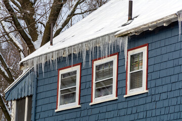 Snow-covered roof with long icicles hanging from a family house facade in winter, Boston, Massachusetts, USA  © Baharlou