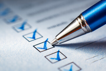 Close-up of a pen marking checkboxes on a survey or form