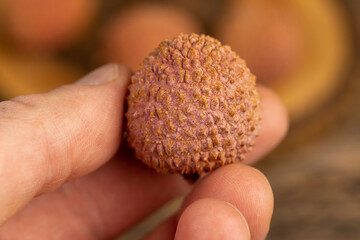 take ripe red lychees scattered on a wooden table, ripe red-skinned lychee fruits,rough textured lychee peel closeup