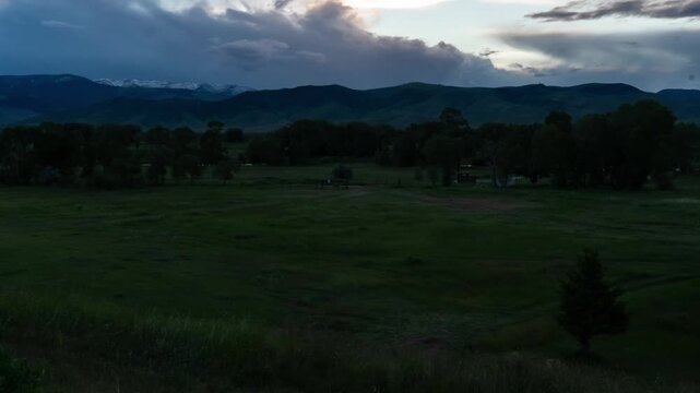 Sunset thick clouds mountains over grass field 