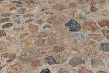 a road made of stones of different sizes in rural areas, a ancient road made of multicolored stones, cobblestones and pebbles