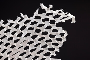 crumpled white paper with a lot of cuts is used for packaging , white paper with cuts and a lot of holes is used for packaging goods and other purposes