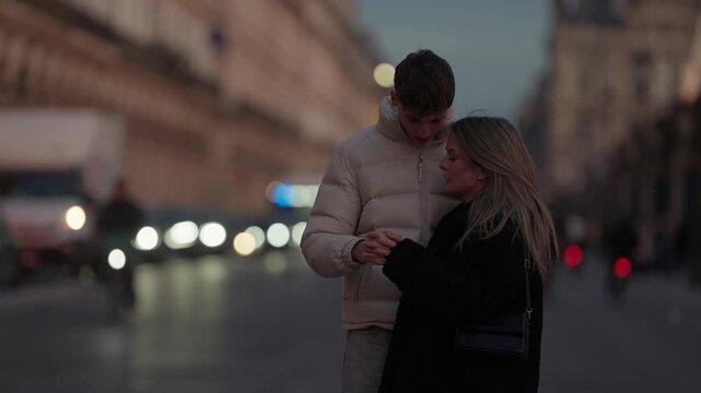A loving couple shares a kiss on a street in Paris France at dusk The background features bokeh lights and a blurred cityscape creating a romantic atmosphere The clip captures a moment of love and aff