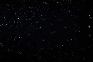 Tiny dust randomly flying in the smoky air, empty space template for objects advertisement. Dust particles of white powder in low light on empty dark black contrast background, close shot.