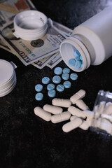 Various pharmaceutical pills and capsules, blue and white, spill from overturned prescription bottles onto a dark background near scattered US hundred dollar bills.