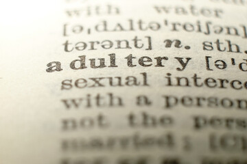 Macro close-up of “adultery” in an English dictionary, concept for infidelity, marriage conflict and divorce.