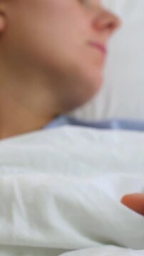 Young female patient resting in a hospital bed with an iv line in her arm, receiving intravenous therapy during her recovery and looking towards the side with a calm expression on her face