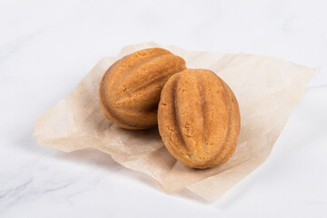 Two cookies in the shape of nuts. Stuffed with boiled condensed milk. On paper. White background. Merry Christmas. New year	