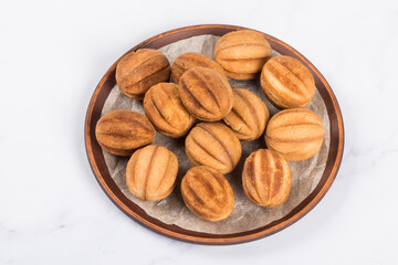 Cookies in the shape of nuts. Stuffed with boiled condensed milk. On a plate. White background. Merry Christmas. New year