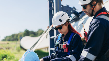 Professional wind turbine engineers preparing and inspecting equipment for installation and maintenance at a renewable energy site, teamwork, clean power, and sustainable technology. © NewSaetiew