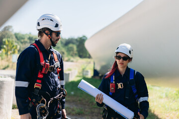 Professional wind turbine engineers preparing and inspecting equipment for installation and maintenance at a renewable energy site, teamwork, clean power, and sustainable technology.