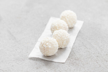 Coconut candy ball with whole almonds inside. On serving paper. On a light background. Close-up