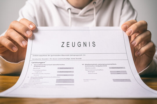 Person h&auml;lt Zeugnis in den H&auml;nden &ndash; Symbol f&uuml;r Bildung, schulische Leistungen und Zeugnisbewertung