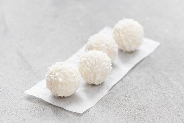 Vegan Coconut candy ball with whole almonds inside. On serving paper. On a light background. Close-up