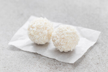 Two Coconut candy balls. On paper. Light background. Close-up