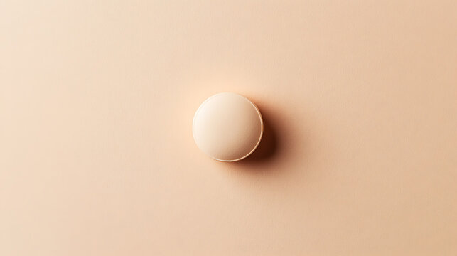 A minimalist still life featuring a round, off-white object placed against a soft, peach-colored background. The composition is clean, emphasizing simplicity and subtle tonality.