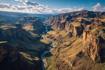 Fototapeta premium Dramatic Canyon Landscape with River and Varied Terrain Under a Cloudy Sky.