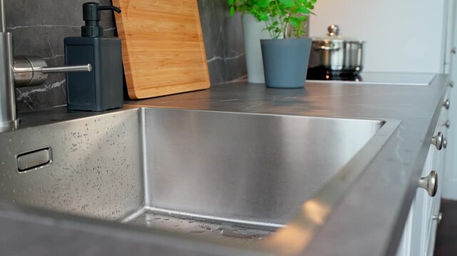 Short clip showing a dishcloth drying a sink in a stylish, simple, modern kitchen.