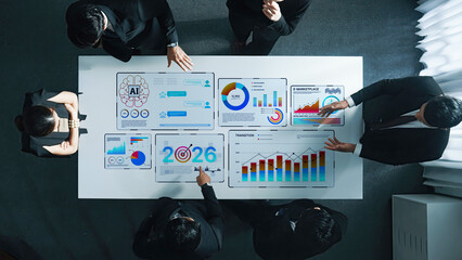 A diverse business team engages in strategic discussion, analyzing data visualizations on a smart table, emphasizing collaboration and technological innovation in a modern workplace. Trope