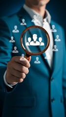 Searching for talent a businessman uses a magnifying glass to examine potential employees