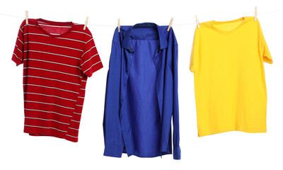 Different clothes drying while hanging on clothesline against white background