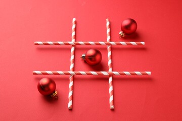 Tic tac toe game made with Christmas balls on red background