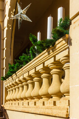 Elegant Balcony Decor With Green Garlands and Tall White Candles Under a Star Ornament