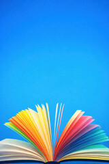 An open book with colorful illustrated pages spreading outward. Conceptual illustration representing education, fantasy, reading, learning, and inspiration, with strong contrast and copy space.