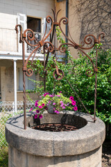 Ornate Rusty Wellhead With Hanging Flower Pot In Garden Scene For Vintage Decor