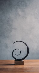 Minimalist Metal Spiral Sculpture on Wooden Base Against Textured Background.