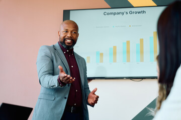 Confident businessman presenting company growth strategy to colleague in boardroom during daytime