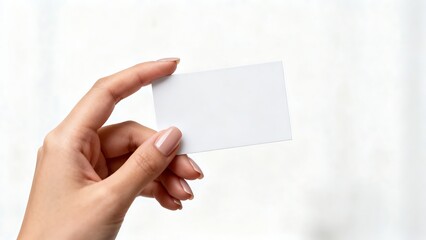 Obraz premium Woman’s hand offering a blank white business card, isolated on white background