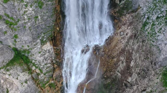 Close aerial view of waterfall flowing into turquoise pool, Slovenia