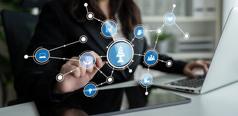 A focused business professional engages with a digital interface, showcasing symbols of entrepreneurship, innovation, and networking in a contemporary office setting. Crux