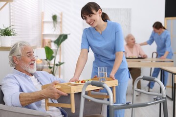 Care worker serving dinner to senior man at retirement home