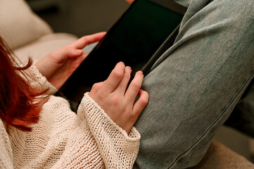 women sitting and holding a tablet in her hand.modern lifestyle.technology in everyday use.remote work or browsing online content © Anna Kondratiuk