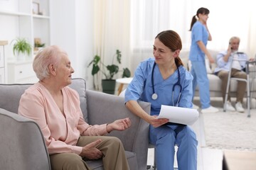 Fototapeta premium Care worker asking senior woman about her wellbeing at retirement home
