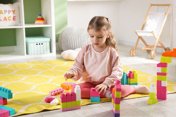 Little girl playing with toys on floor in playroom