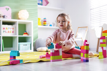 Little girl playing with toys on floor in playroom