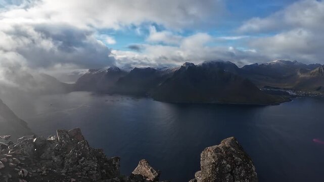 Stunning aerial perspective of clouds flowing over majestic mountains and a deep blue fjord in Norway